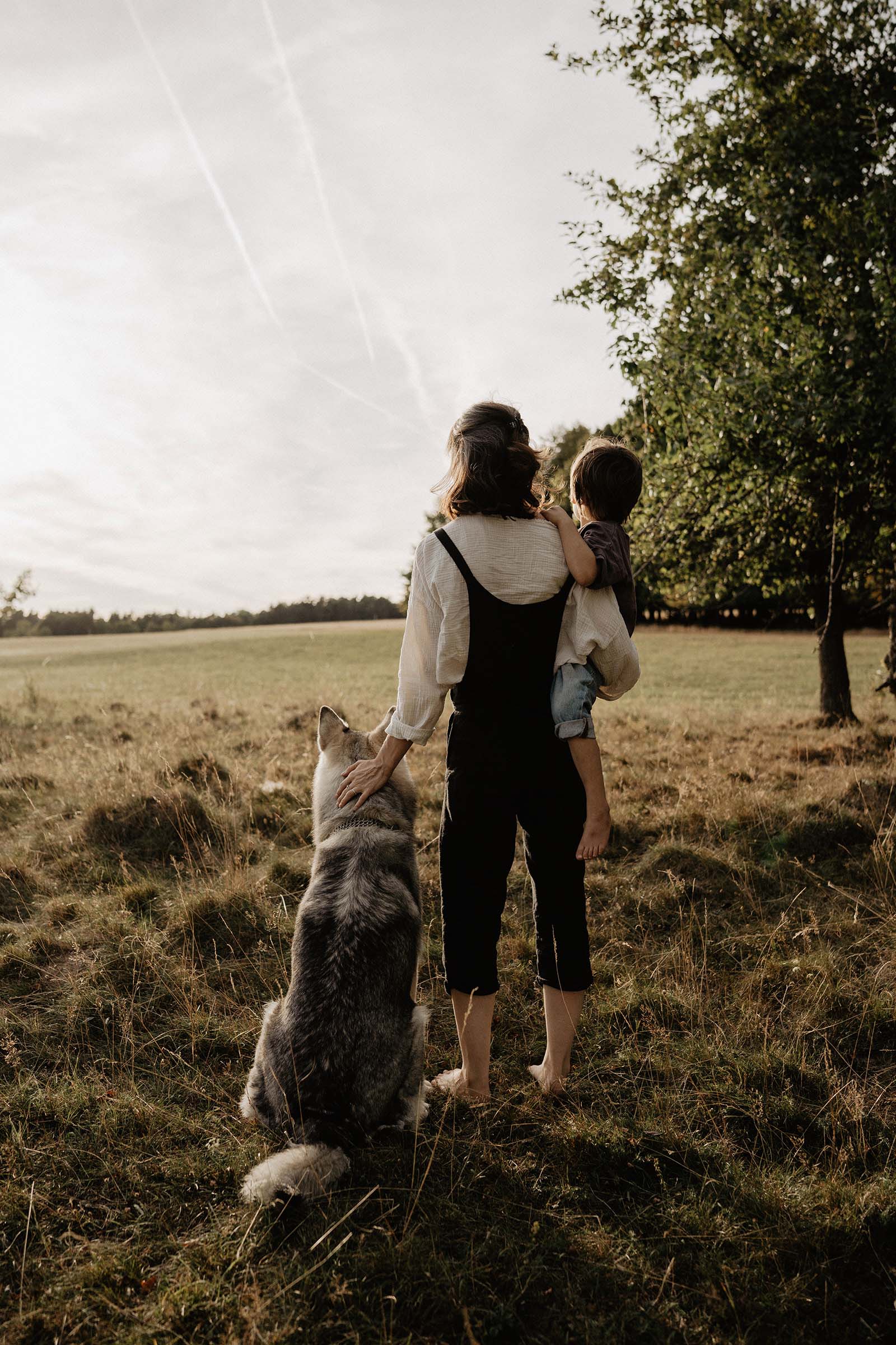 Portrait von Fotografin Carolina aus Fürth zusammen mit ihrem Husky und Sohn auf dem Arm an einem Sommerabend