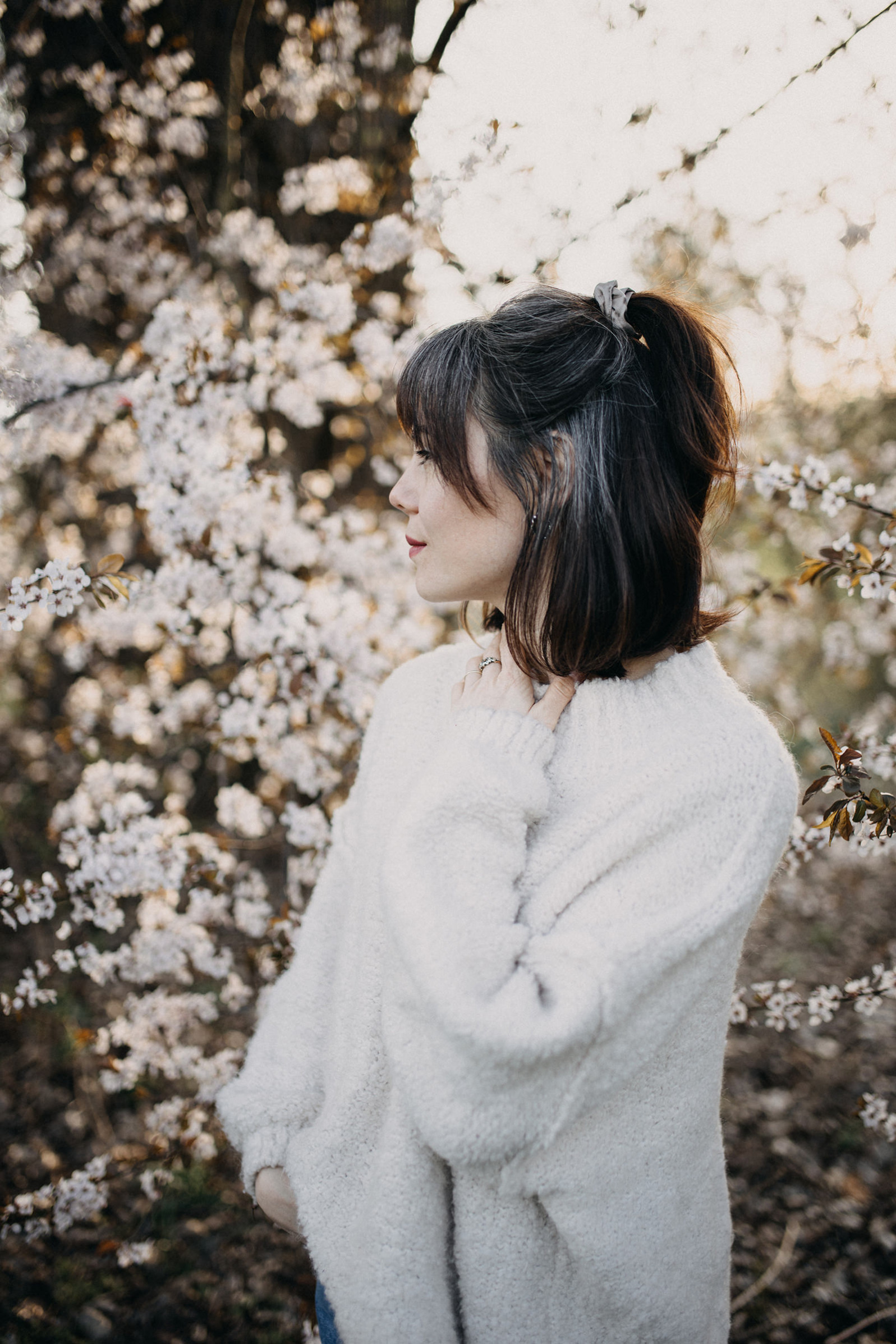Portrait von Fotografin Carolina aus Fürth im Frühling mitten in den Kirschblüten und ihren weißen Haaren.