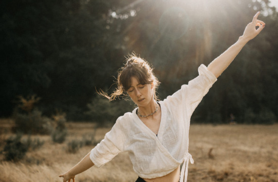 Losgelöstes und ausgelassenes Portrait einer Yogalehrerin in Bewegung und tanzend in der Abendsonne