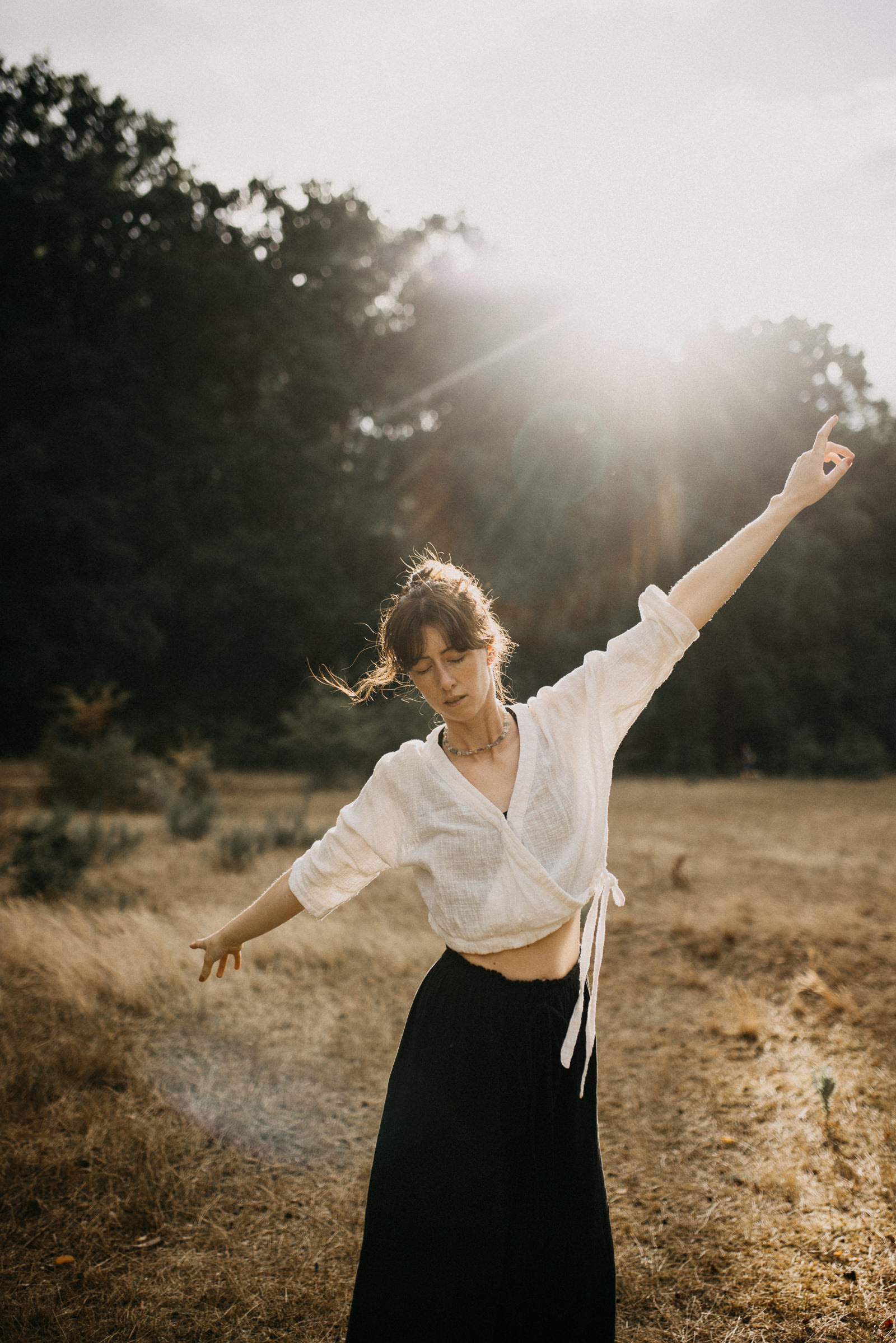Losgelöstes und ausgelassenes Portrait einer Yogalehrerin in Bewegung und tanzend in der Abendsonne