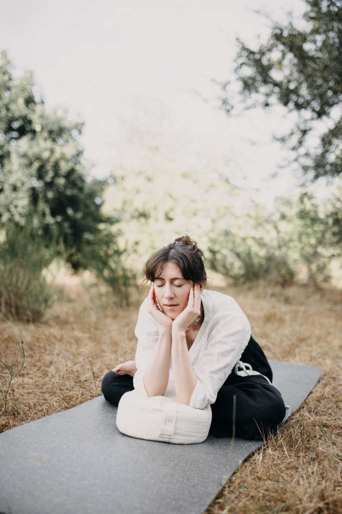 Ruhiges Portrait einer Yogalehrerin in einer Yin Yoga Haltung draußen in der Natur