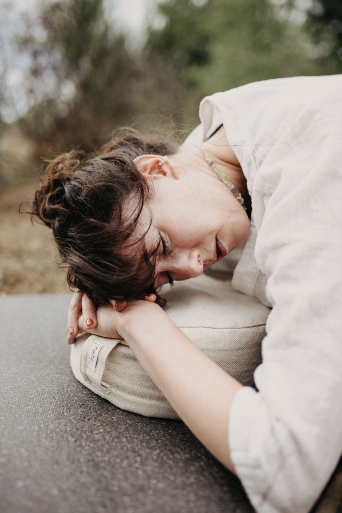Ruhiges Portrait einer Yogalehrerin in einer Yin Yoga Haltung draußen in der Natur