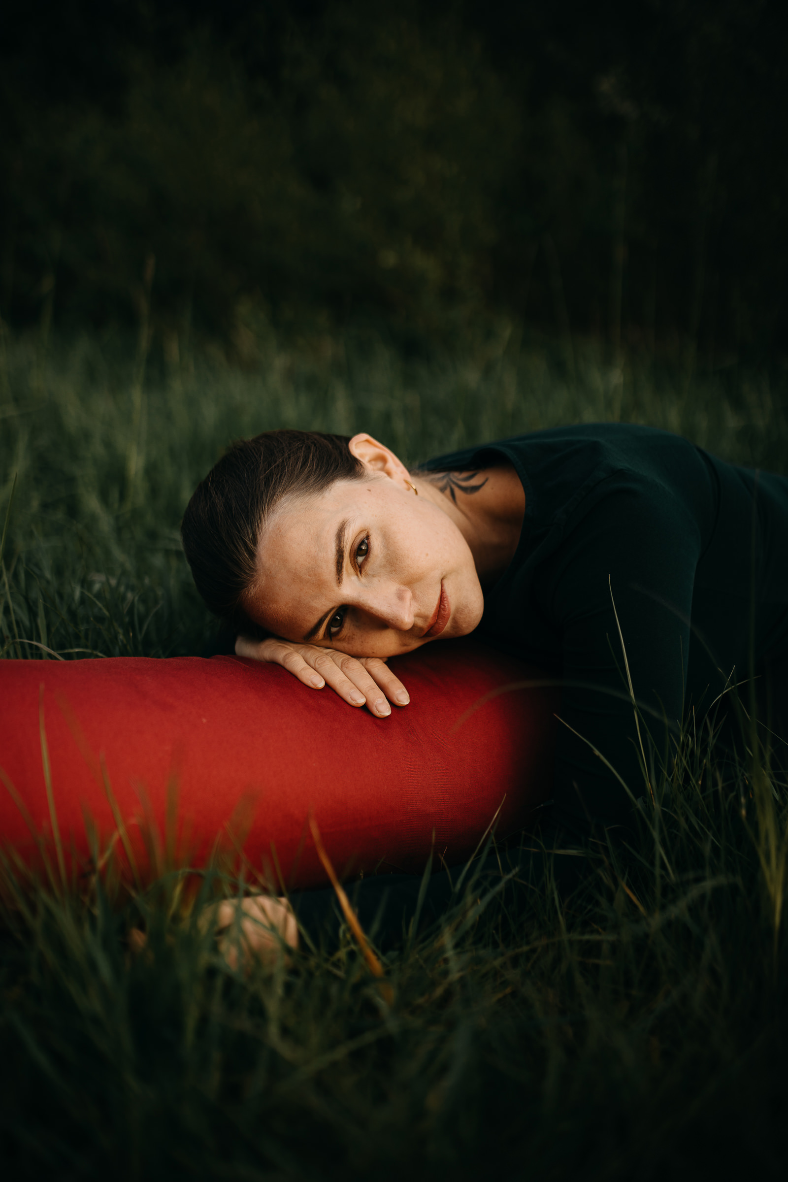 Ruhiges Portrait in einer Yin Haltung der Yogalehrerin Elisa Körpergefühl wie sie auf einem Bolster liegt