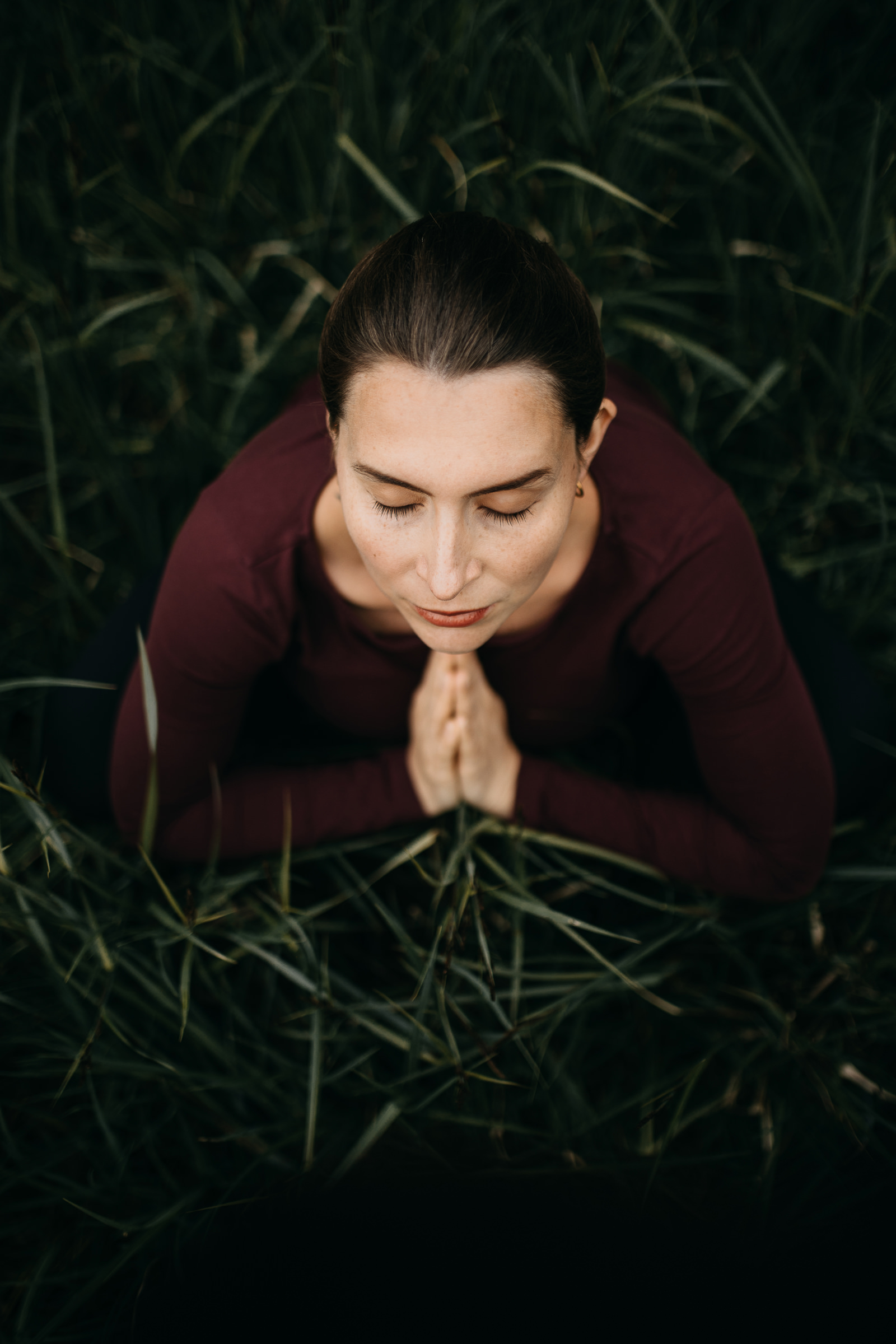 Yogaportrait von Elisa von Körpergefühl mit geschlossenen Auggen im hohen Gras sitzend, von oben fotografiert