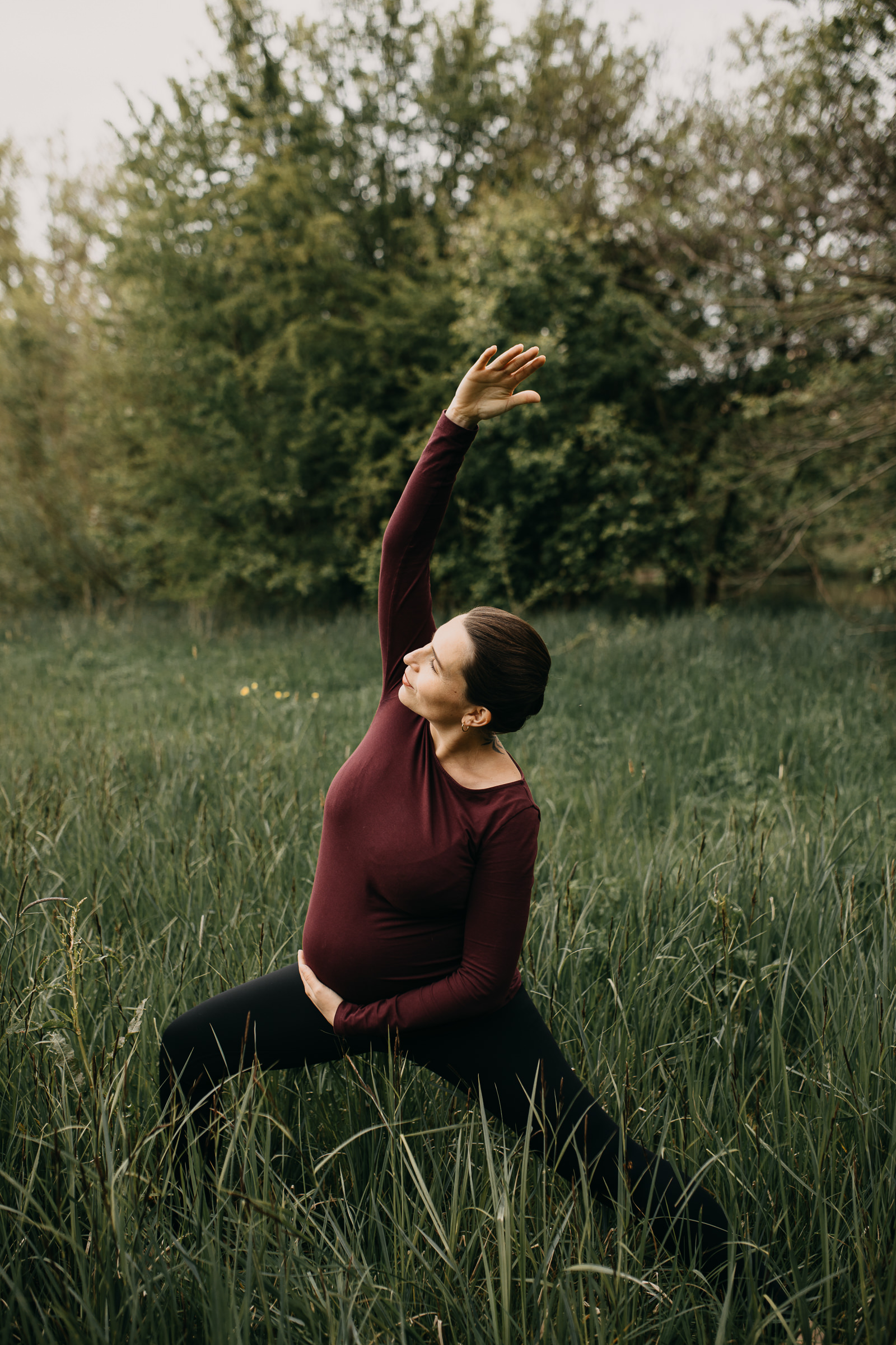Yogaportrait von Elisa von Körpergefühl im Gras stehend, mit Babybauch im hohen Gras stehend